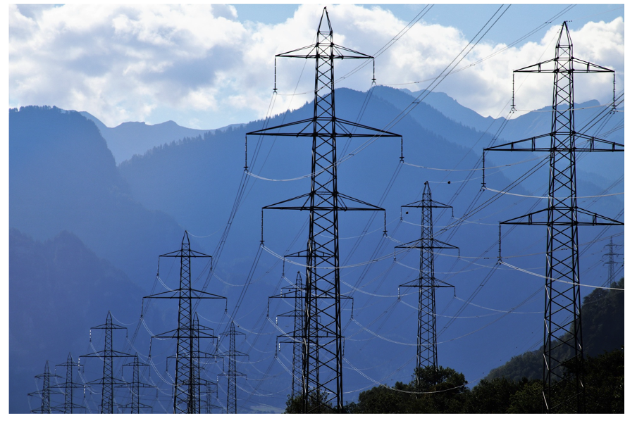 electricity poles and lines in front of a mountain chain